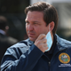 Florida Gov. Ron DeSantis takes his mask off as he prepares to speak during a press conference at the Hard Rock Stadium testing site on May 06, 2020 in Miami Gardens, Florida.